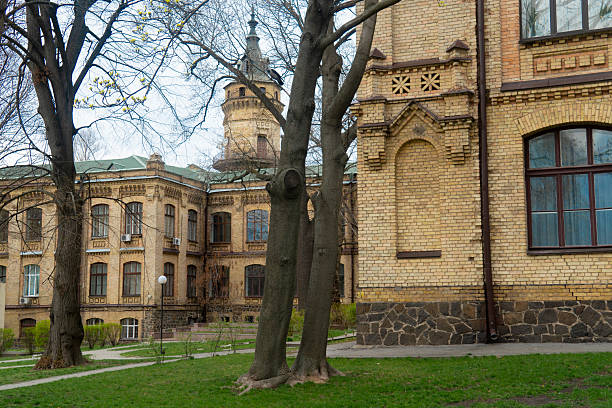 Kyiv. Kyiv Polytechnic Institute. Large, yellow brick building with detailed architectural features, numerous windows, and surrounding green lawns and trees on a cloudy day