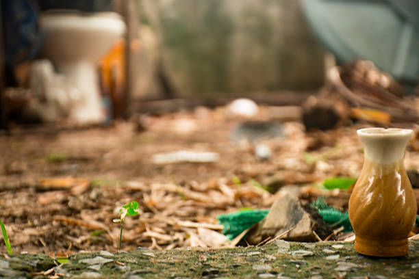 Old concrete pavement covered with dried leaves, with an old vase sitting next to it.