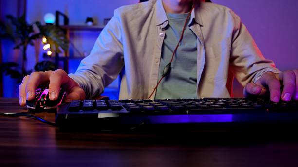 istock Person Engaged in Illuminated Computer Gaming Setup at Home 2234338511