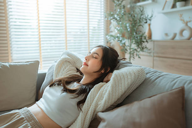 istock Relaxed young Asian woman lying on comfortable sofa at home, enjoying peaceful weekend alone in cozy living room, carefree relaxation and wellness lifestyle 2234346443