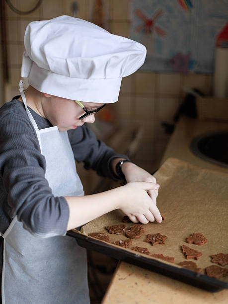 istock Boy arranging gingerbread cookies on baking tray 2234348069