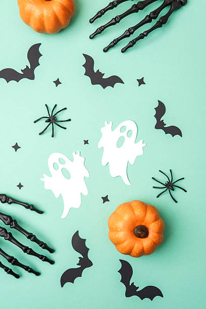 istock Orange pumpkins, white ghosts, black bats, spiders and skeleton hands on a mint green background 2234350627