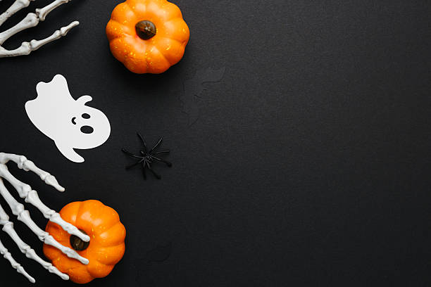 istock Halloween decorations pumpkin ghost spider skeleton hands on black background with copy space 2234350631