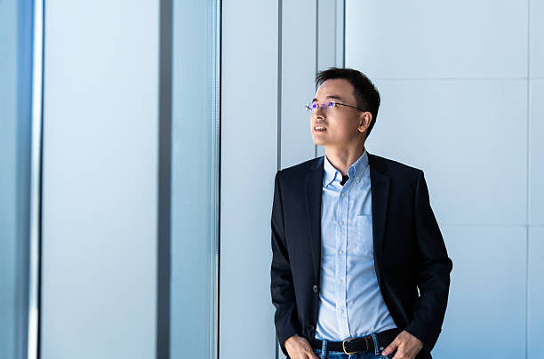 istock Businessman standing in office with hands in pockets 2234352916