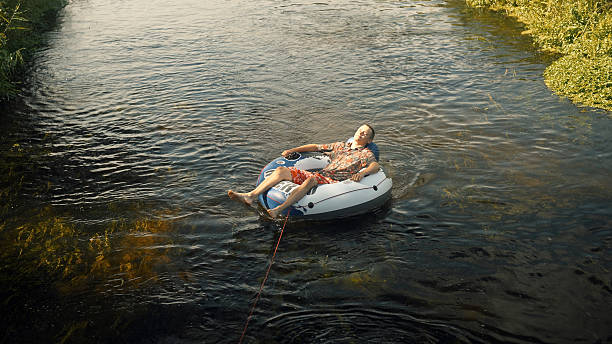 istock Summer vacations river adventure. Man on an inflatable tube being pulled by a boat or kayak off screen 2234354367