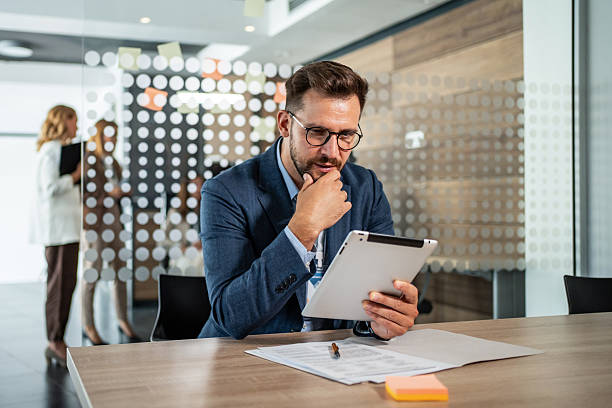 istock Businessman reading information on digital tablet in modern office 2234354417