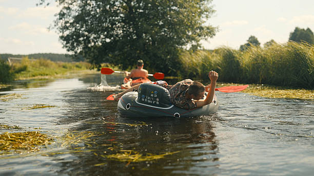 istock Summer kayaking adventure. Paddling together and having fun pulling a man relaxing on an inflatable tube 2234354985