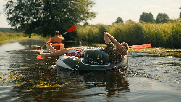 istock Summer kayaking down the river. Paddling together and having fun pulling a man relaxing on an inflatable tube 2234354986