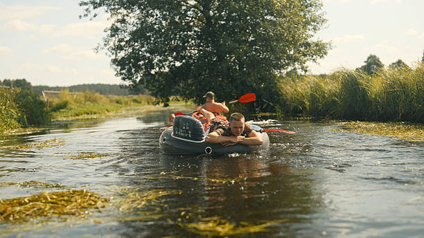 istock Summer kayaking adventure down the river. Paddling and having fun pulling a man relaxing on an inflatable tube 2234355012