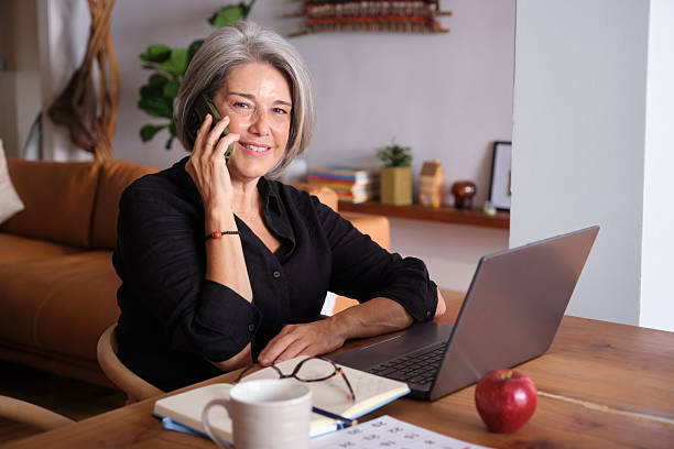 istock Happy senior woman working remotely using laptop and mobile phone 2234355918