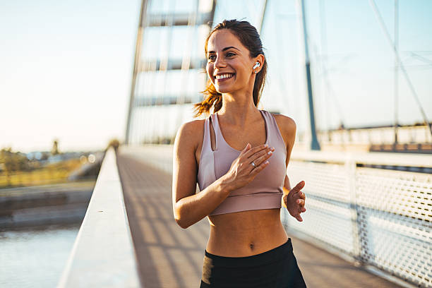 istock Young Woman Smiling While Jogging Over a Modern Bridge Outdoors 2234365740