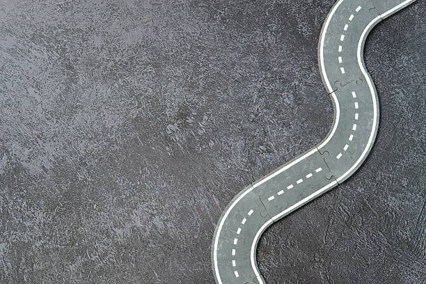 istock Miniature toy road with white markings on textured dark surface. 2234371746