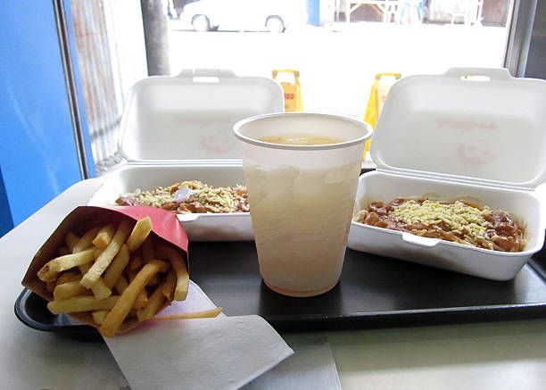 A serving of French fries, a cold drink in a disposable cup, and two takeout containers of spaghetti topped with sauce and grated cheese are seen on a tray at a fast-food restaurant. In Daveo City, Philippines, On March 21, 2012