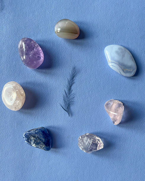 istock Black feather surrounded by natural healing stones on blue background 2234373817