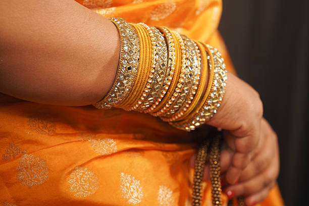 istock Elegant gold bangles complement vibrant orange attire at celebration 2234376465