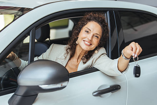 istock Happy Woman Holding Keys Smiling Inside a Modern White Compact Car 2234378077