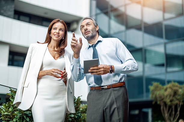 istock Business professionals discuss project ideas outside a modern office building during a sunny day 2234380746