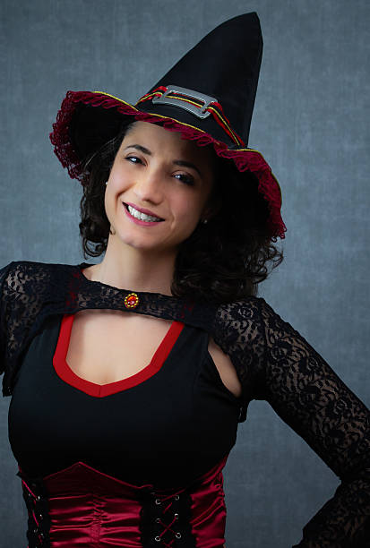 istock Cheerful witch in black and red costume, smiling and looking at camera. 2234381009