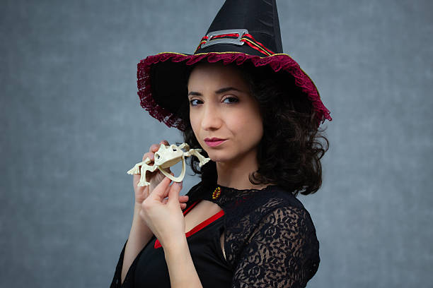 istock Charming witch holding a frog skeleton with a wicked smile. 2234381011