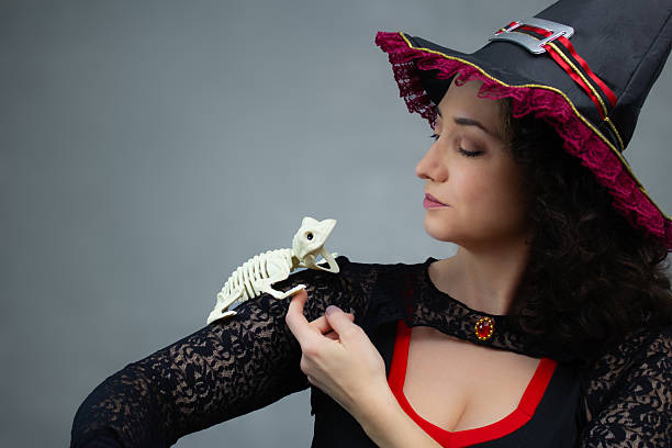 istock Beautiful witch petting a frog skeleton on her shoulder. 2234381013