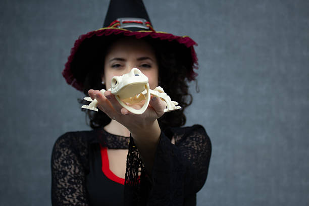 istock Halloween witch holding a funny and happy frog skeleton. 2234381015