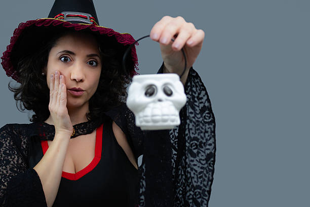 istock Funny witch amazed holding a skull-shaped small basket. 2234381020