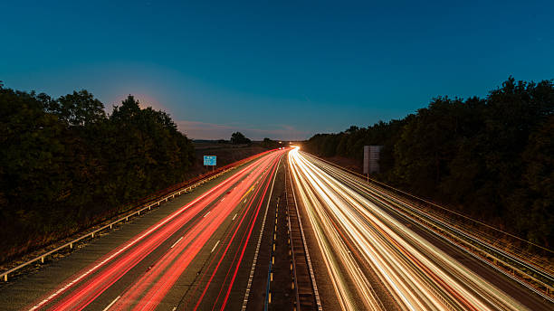 istock Light trails illuminating highway at dusk with moon in the background 2234381459