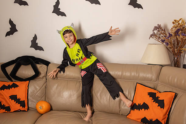 istock Child wearing monster costume posing on sofa during halloween party 2234384791