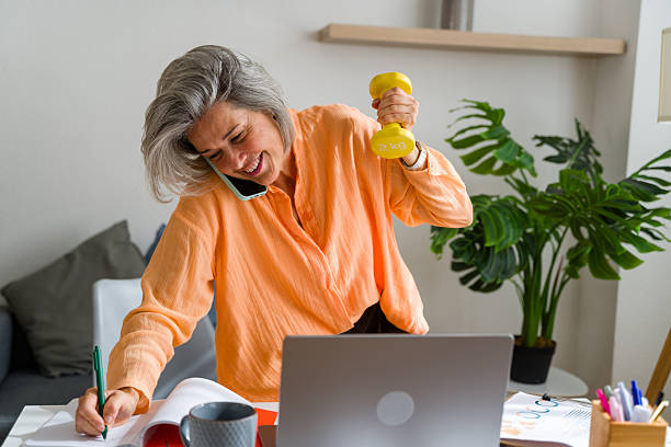 Mature businesswoman multitasking, working and exercising at home office