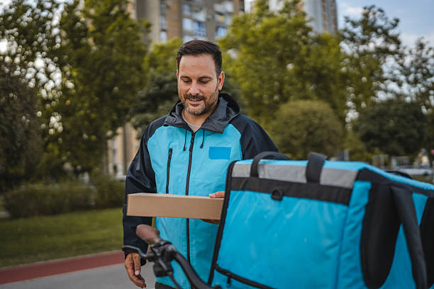 istock Delivery man placing pizza box in thermal backpack on bicycle 2234386593