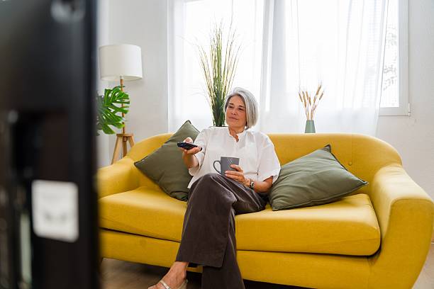 istock Mature woman relaxing on sofa watching television and drinking coffee 2234386742