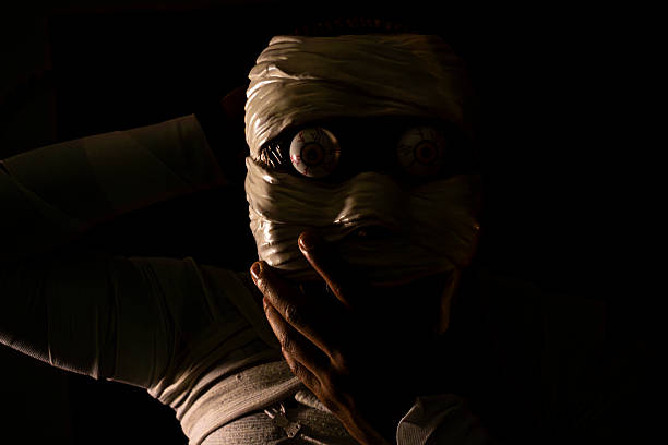 istock Creepy mummy wrapped custom with bandages taking his mask 2234387841