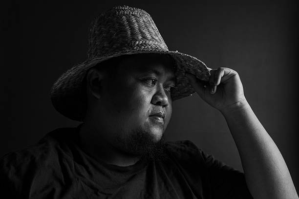 istock Male profile view with straw hat touching brim, monochrome black and white image, vintage portrait style, symbol of respect, contemplation, and thoughtful gesture. 2234392191
