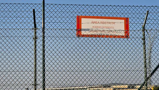 istock A security fence with barbed wire marks the perimeter of a restricted area, as indicated by a warning sign stating 