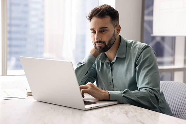 istock Focused man sitting at desk review information received in e-mail 2234395186