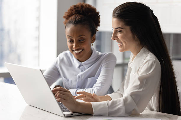istock African and Latina women teammates engaged in teamwork using laptop 2234396565