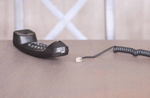 istock Corded telephone with disconnected cable resting on a wooden surface in a simple interior space 2234399059