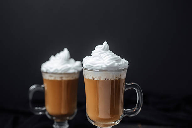 istock Two hot drinks with whipped cream in clear mugs on a dark backdrop 2234399160