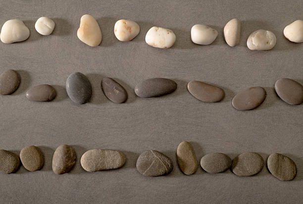 A close-up macro shot of smooth, colorful pebble stones arranged on a white background, showcasing their natural textures and intricate details.