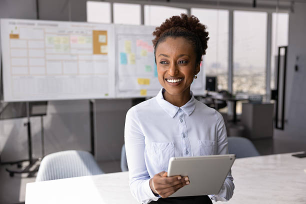 istock Smiling office employee standing in modern meeting room with tablet 2234400611