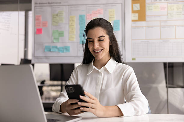 istock Professional woman sits at desk using smartphone with contented smile 2234400810