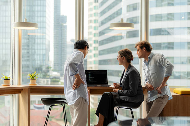 istock A group of business people from different backgrounds converse in a bright office setting by floor-to-ceiling windows. The dynamic scene emphasizes innovation, strategy, communication, and professional teamwork in a high-rise business district. 2234406084