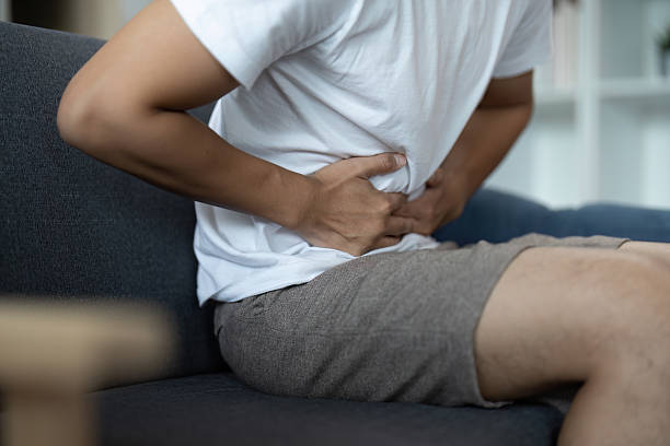 istock Physical Health. Young man suffering from back pain while sitting on couch. 2234407072
