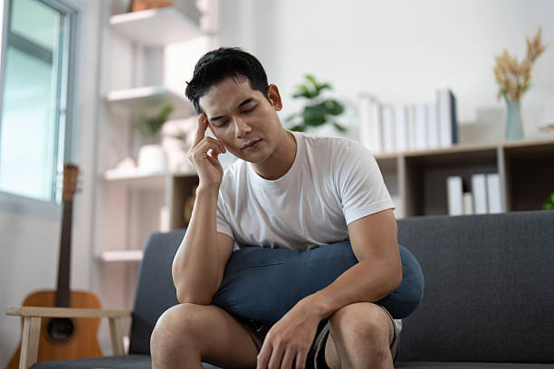 istock Emotional Reflection. Young man seated, expressing thoughts while holding a pillow. 2234408806