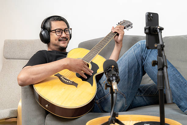 istock Young man live streaming guitar performance on smartphone at home 2234418256