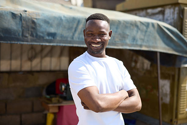 Portrait of smiling tailor standing with arms crossed. Confident man in casuals at sunny day. He is wearing white t-shirt.