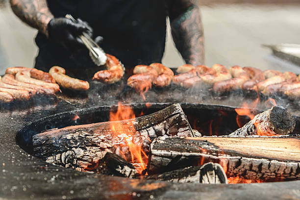 istock Grilled sausages cooking on an open fire pit with wood logs and glowing embers 2234420645