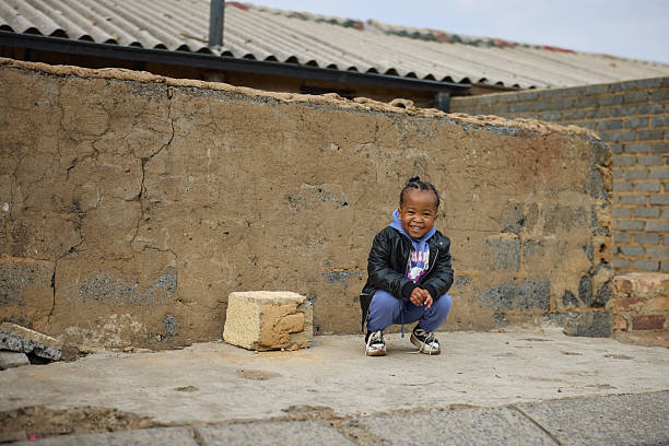 Full length portrait of smiling girl crouching in front of wall. Playful girl is spending leisure time. She is wearing casuals along with leather jacket.