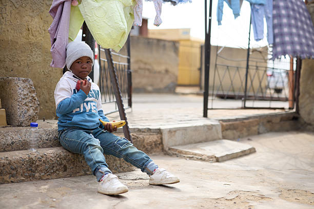 A small child sits on a sidewalk in Rwanda, Africa.