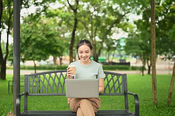 istock Cheerful female freelancer enjoying remote work outdoors with coffee and laptop 2234422610
